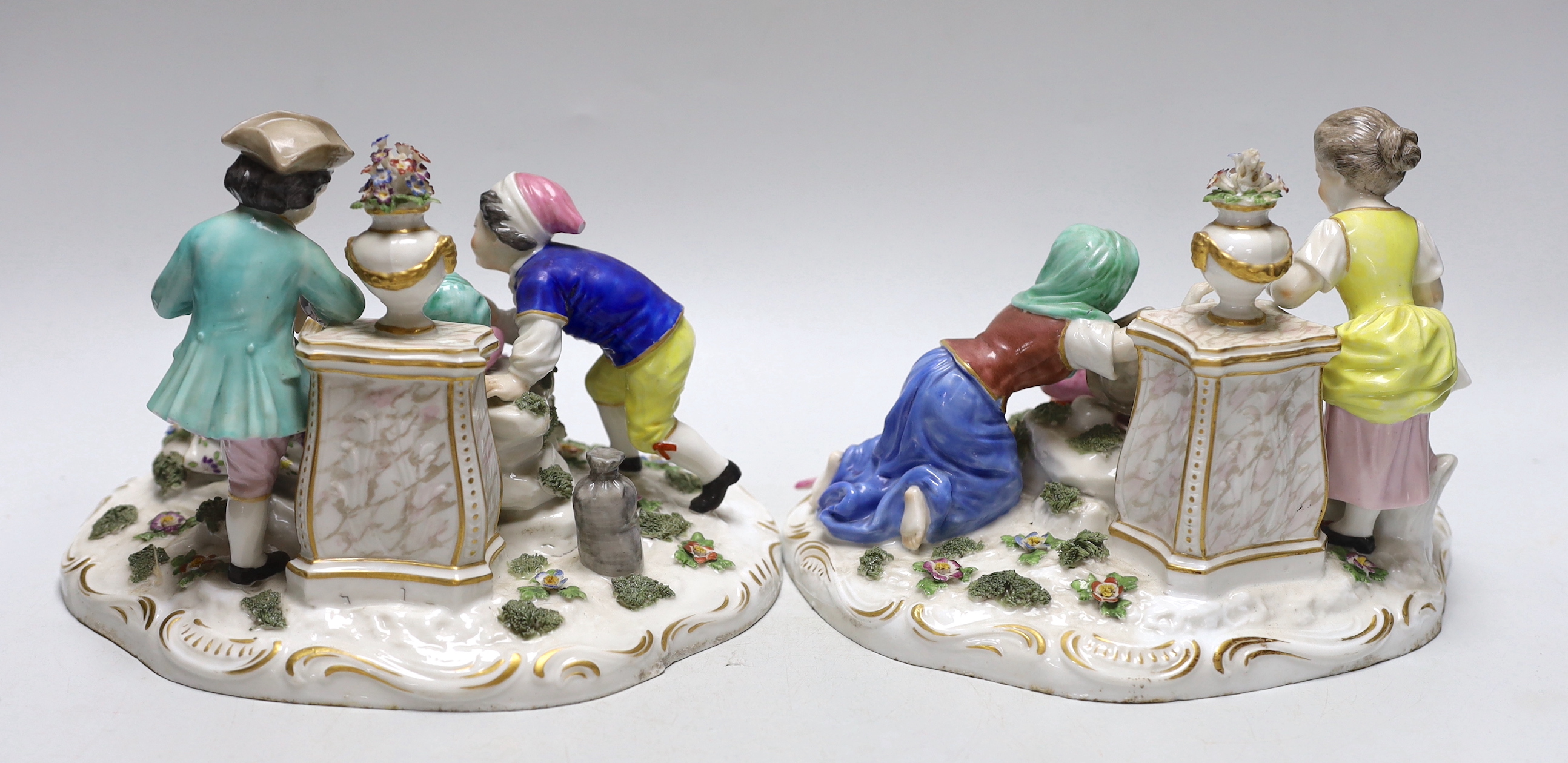 A pair of German porcelain figure groups of children wearing 18th century dress, each with floral encrusted decoration, each 22cm wide